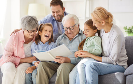 Happy big family, gathering at home on sofa, laughing three generations got printed album, viewing...