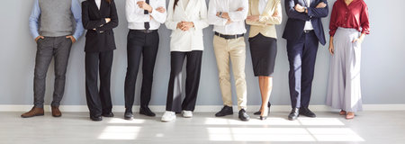 Midsection shot of a diverse group of business people stands together on a grey background. Team highlights office teamwork, community collaboration between staff, and a professional work environment.の写真素材