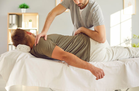 Rehabilitation back, shoulder massage, corrective exercise reducing pain, sport injury, joint health, fix muscle imbalance. Nurse, manual therapy doctor helping patient training, restoring conditionの写真素材