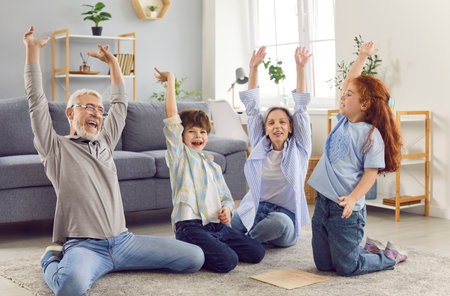 Grandma and grandpa are having fun at home with their grandchildren. Happy children sitting on the...