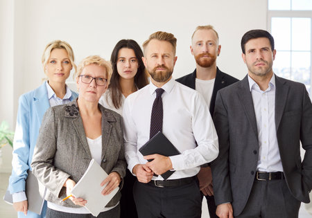Confident looking diverse professional business team standing in modern office, looking at camera, young and old teambuilding workers staff group together, human resource corporate portrait in officeの写真素材