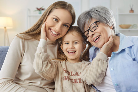 Closeup portrait of happy family of mother, grandmother and child girl hugging while resting on...