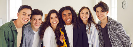 Portrait of a group of happy smiling diverse high school students and classmates in casual clothes standing together in a row and looking cheerful and positively at camera.の写真素材