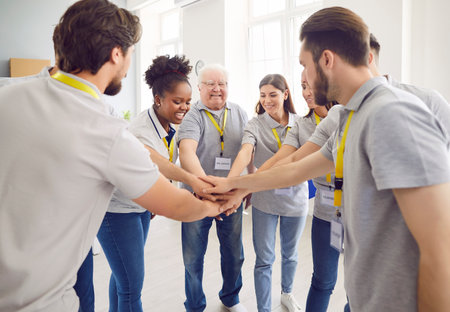Team of volunteers standing in circle putting their arms in a stack working in community charity center. People volunteering in food bank. Humanitarian aid and social help for poor concept.の写真素材