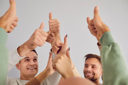 Thumb up happy friends closeup gesture of approval, encouragement, young people group raising thumb showing agreement. Smiling people expressing positivity, idea approval, business team achievementの写真素材