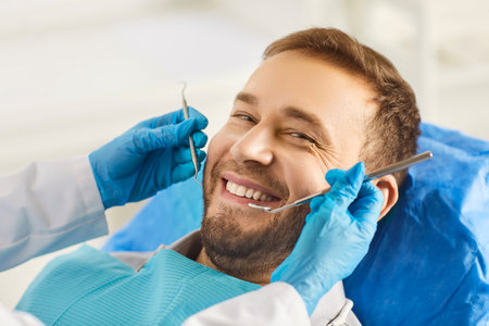 Portrait of happy smiling man looking cheerful at camera sitting in dentistry clinic during medical check up. Close up of male patient treating teeth at dentist office. Teeth care concept.の写真素材