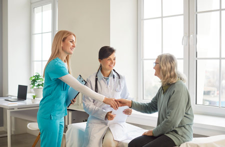 Doctor and nurse meet mature senior sick woman in their clinic, give professional consultancy and talk about future treatment. Old female pensioner has health check up in hospital.の写真素材