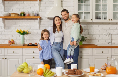 Happy family portrait, young couple and kids in modern home kitchen, healthy eating habits, enjoy cooking in modern place, culinary hobby, variety of nutritious foods, snacks, and drinks on deskの写真素材
