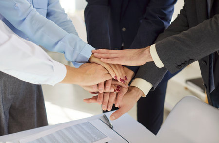 Cropped shot of business people team standing in circle, stacking hands on top of each other. Group...