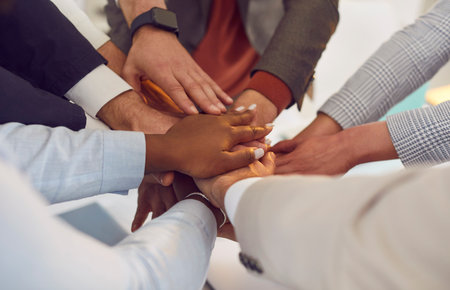 Close up shot of a multiethnic business team stacking hands together in a circle. The group of people in the office demonstrates teamwork and unity, emphasizing collaborative efforts.の写真素材