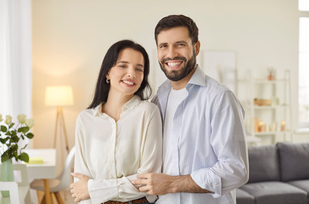 Happy smiling family, beard man husband and wife in close hug to enjoy tender romantic moment in living room, loving couple in domestic atmosphere at home, having romance together, good relationshipsの写真素材