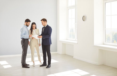 Married family couple of clients consulting with a realtor or agent while visiting a new property or house, focusing on purchasing decisions and the potential of real estate investments.の写真素材