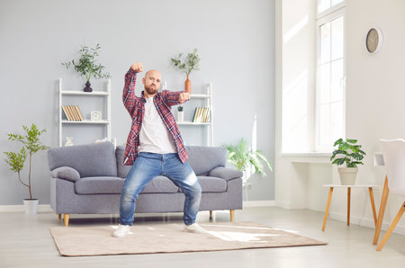 Positive man dancing alone at home, enjoying a fun and active and happy leisure time. With music playing, he creates own lively party atmosphere, expressing happiness and joy through dance.の写真素材