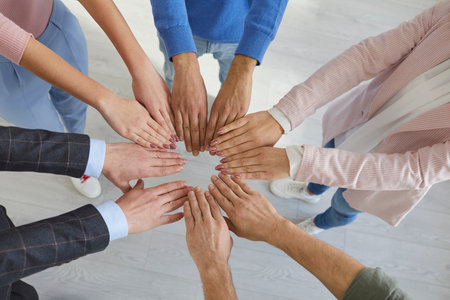 Team of people putting their hands together. Group of men and women standing in circle and joining their hands. Cropped high angle close up shot from above. Community, teamwork, business union conceptの写真素材