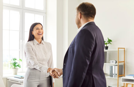 Happy office shaking successful smiling business candidate hand at meeting congratulating with getting new job manager making great deal with customer, diverse partners greeting, professional coworkerの写真素材