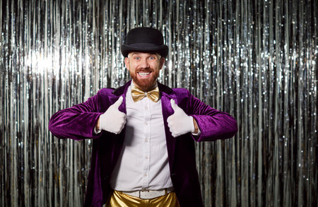 Portrait of smiling happy man in purple costume showing thumb up on shiny background during evening party, filled with fun in a lively setting with energy and joy every moment of celebration.の写真素材