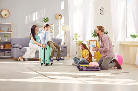 Happy and satisfied family with children is getting ready for summer vacation, packing suitcases and making preparations for the trip. Excited for the holiday adventure, gather together at home.の写真素材