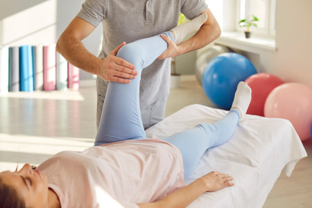 Rehabilitation knee, leg massage, corrective exercise reducing pain, sport injury, joint health, fix muscle imbalance. Nurse, manual therapy doctor helping patient training, restoring good conditionの写真素材
