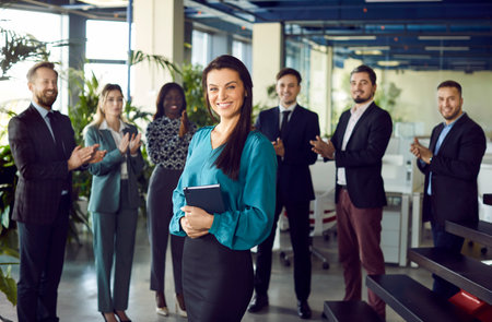Confident lady, successful business trainer coach, leader, diverse team applauding after presentation for female speaker consulting clients, teaching employees, training company people, modern officeの写真素材