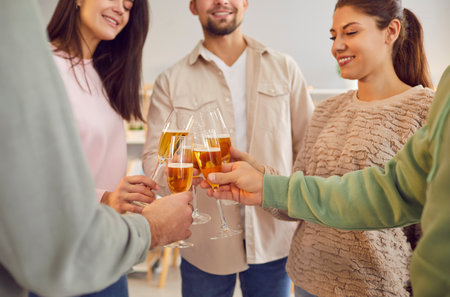 Close up view of Caucasian people hands holding glasses, clinking them together and cheers in a cheerful toast at a party or event. The group is enjoying wine and celebrating holidayの写真素材
