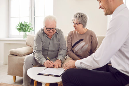 Happy elderly clients finalize decision by signing a contract with a trusted agent, adviser, or consultant. Satisfaction with the investment and insurance options discussed during the meeting.の写真素材