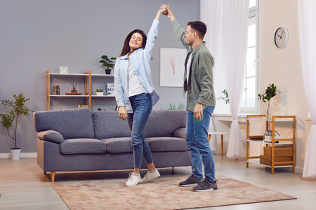 Happy couple dancing together at home, enjoying music and each others company. Their love and joy shine through as they share this fun and leisurely moment, making memories filled with dance.の写真素材