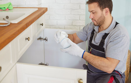 Professional plumber focuses on working at home in kitchen, providing service for sink and pipes, addressing leak issues with maintenance in a dedicated and efficient manner daily.の写真素材