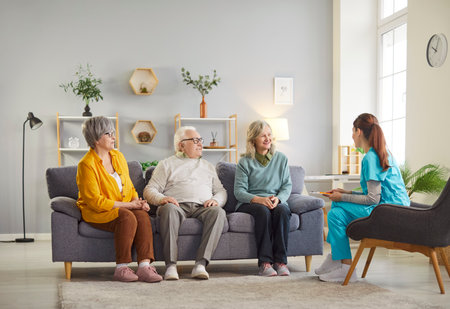 Caring female doctor or nurse providing a group consultation for senior patients at a nursing home. Healthcare help, medical advice, and assistance in a professional and caring setting.の写真素材