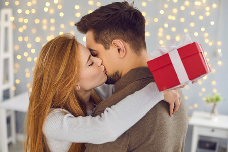 Side view close up of a beautiful young woman hugging and kissing her husband on the cheek in gratitude for a gift. Concept of exchanging gifts for Valentines Day, Christmas or birthday.の写真素材