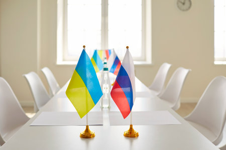 White table with flags of Ukraine and Russia in empty negotiation room. Office interior before meeting of diplomats who are going to work towards ending war and conflict resolution. Nobody, no peopleの写真素材