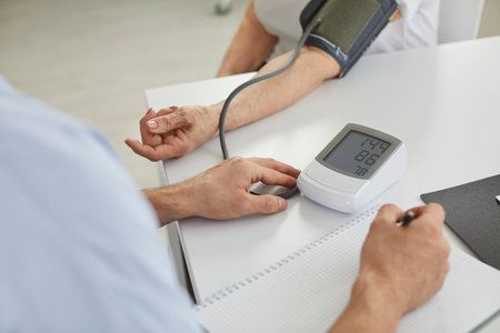 Medical and healthcare. Doctor measures blood pressure of elderly woman using electronic digital measuring device. Close up of tonometer on table with measurement indicators on digital monitor screen.の写真素材