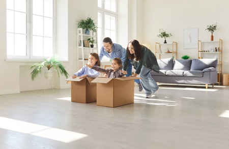 Joyful family and kids together enjoying leisure. Children riding in boxes, playing, and having fun. Home entertainment and quality time in a joyful and relaxed domestic environment.の写真素材