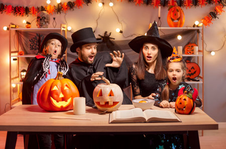 Halloween family holiday bewitchery, magical spell, parents, funny kids with pumpkin lantern in scary costumes for dress ups party night event, spooky monster, horror cosplay look, charm, enchantmentの写真素材