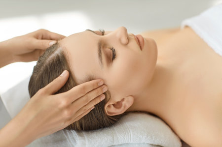 Cosmetologist gently massages female temple muscles performing face, head spa massage, skin, relaxed girl getting rejuvenating in salon, clinic, therapist helping with headache pain, relaxationの写真素材