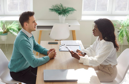 Multiracial interview talk, female hr manager, smiling african american woman at negotiations, positive people in modern office, starting partnership, teamwork and business etiquette, client agreementの写真素材