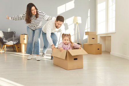Happy family moving new flat holding boxes, cardboard boxes fun, couple and child overjoyed celebrating new house apartment, buying, renting comfortable accommodations, spacious modern living spaceの写真素材