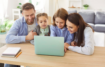 Happy family with little kids spending time together at desk in living room with laptop, watching screen planning holiday, learning online, apps users, shopping services and goods, orderingの写真素材