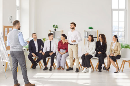Office meeting, business team leader coaching, mentoring, talking to diverse people to explain strategy at corporate group meeting, staff listen to boss, instructing new interns at briefing, shareの写真素材