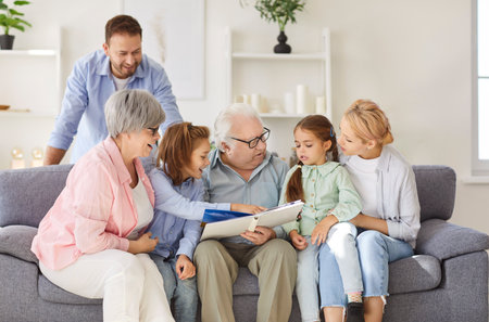 Large family gathers to look through a photo album, sharing memories and bonding over past moments. Love, togetherness, and remembrance captures connection and leisure time at home.の写真素材