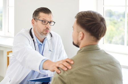 Doctor or nurse in communication and talking with a patient, providing medical support and advice in a hospital setting. Healthcare professional ensures the patient receives proper care and guidance.の写真素材