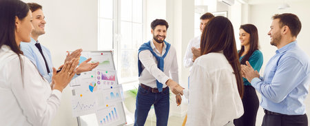 Happy smiling company employees making deal in modern office shaking hands. Business people rejoicing at a successful partnership with a colleagues applauding them on a meeting. Banner.の写真素材