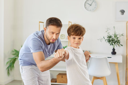 Portrait of a father and son engaged in martial arts training together at home. They practice fighting techniques, bonding through exercise and building strength during active workout.の写真素材