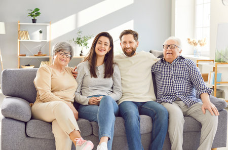 Family portrait of multi generational relatives people at home, mature woman, man in hug of elderly father, mother, senior parent sitting on sofa for understanding, care, family unity and supportの写真素材