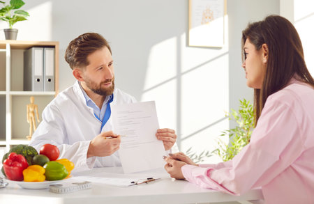 Doctor nutritionist consults with a patient in hospital office, creating a diet and meal plan. The nutritionist provides care, advice, and recommendations for improved health and dietary habits.の写真素材