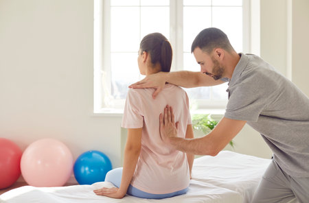 Manual therapy back spinal injury rehabilitation, physical therapist manipulative therapy in medical clinic room. Chiropractor or physiotherapist helping patient with scoliosis, pain, spine problemsの写真素材