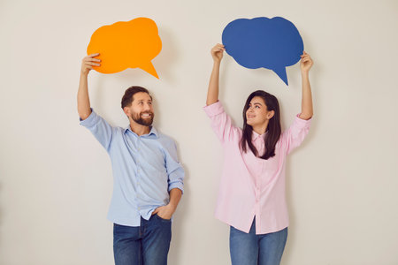 Young happy couple with paper speech balloons above, man, woman pair happy communication, dialog. People convey information, express feeling, good conversation, discourse, chatting in close relationsの写真素材