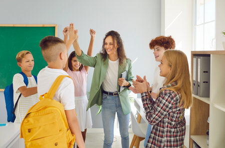 Dedicated teacher, surrounded by a circle of smiling students group, shares high five with each pupil after a lesson. The scene captures the essence of positive unity and teamwork.の写真素材