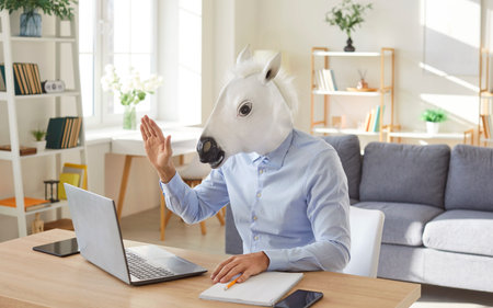 Funny extravagant happy man wearing horse head looking at computer screen waving hello, holding video call with client, call center service support agent meeting for conference, discussionの写真素材