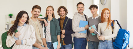Happy university students with notebooks and backpacks standing next to each other in row in room, being friendly groupmates, satisfied after successfully passed exams. Education conceptの写真素材