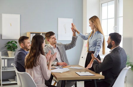 Business people in group and team give high five while working during meeting in office, showcasing teamwork in a professional setting with focus on collaboration and achievement.の写真素材